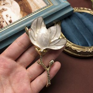 KEQIU Antiqued Gold Magnolia Brooch, Cream Pearlized White Enamel Blossom on Textured Branch Stem, Retro Inspired Floral Statement Jewelry